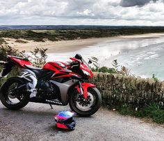 a red motorcycle parked on the side of a road next to a body of water