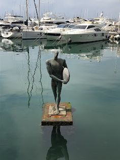 the statue is holding a surfboard in his hand and it's reflection on the water