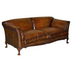 a brown leather couch sitting on top of a white floor