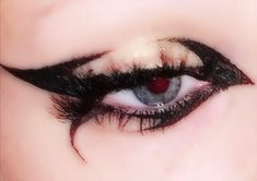 a woman's eye with long black lashes and red eyeshadow on her face