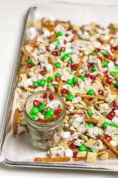 a glass tray filled with lots of candy and pretzels next to a jar of marshmallows