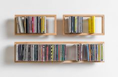 three wooden bookshelves filled with various types of cds and dvds on white wall