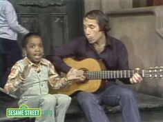 a man sitting next to a little boy holding a guitar