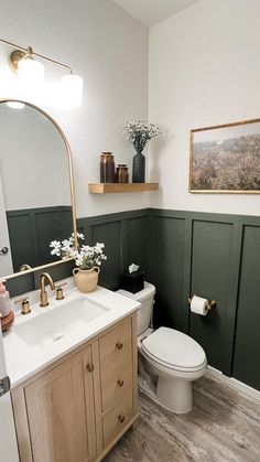 a white toilet sitting next to a sink in a bathroom under a large mirror above it