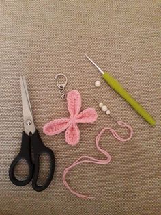 crocheted items are laid out on the floor next to scissors and knitting needles