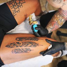 a man with tattoos on his legs is getting ink done by an artist in black gloves