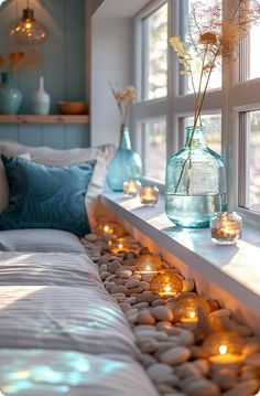 a window sill filled with lots of candles next to a bed covered in pillows