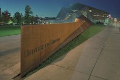 the university of minnesota campus sign is lit up at night with buildings in the background