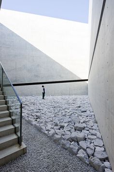 there is a man walking down the stairs in front of some rocks and stone steps