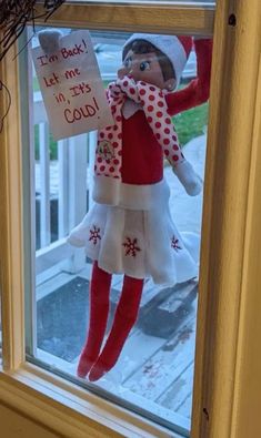 an elf is hanging on the window sill with a sign that says i'm back let me in, it's cold