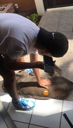 a man is bending over to touch an elephant's tail with his phone in front of him