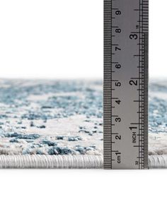 a measuring tape is on top of a rug with blue and white carpeting in the background