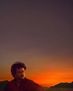 a man standing on top of a hill at sunset