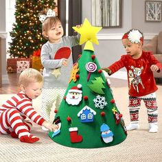 three children are playing around a christmas tree