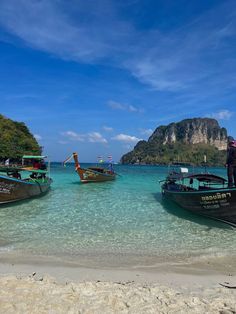 several boats are docked on the beach near an island in the ocean with clear blue water