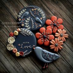 three decorated cookies sitting on top of a wooden table next to an orange and blue bird