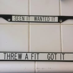 two black and white street signs mounted to the side of a tiled wall in a bathroom