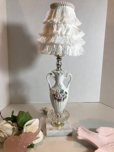 a white lamp sitting on top of a table next to a pink flower pot and vase