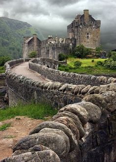 an old castle with stone walls and green grass in the foreground, on a cloudy day