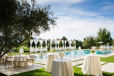 an outdoor dining area with tables and chairs next to a swimming pool in the background