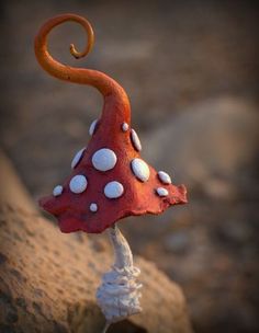 a red mushroom with white dots on it's head is sitting on a rock