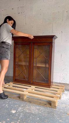 a woman standing next to a wooden cabinet