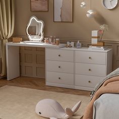 a white dresser sitting next to a bed in a room with pictures on the wall