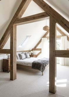 an attic bedroom with white carpet and wooden beams on the ceiling, along with a large bed