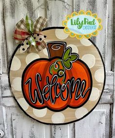 a welcome sign hanging on the side of a wooden door with polka dots and a bow