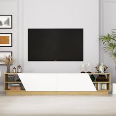 a living room with a large flat screen tv mounted on the wall next to a plant