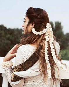 a woman with long hair wearing a white dress and pearls in her hair is standing on a balcony