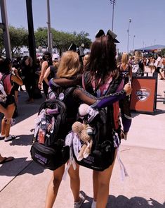 two women in black and pink outfits are hugging each other with their backs to the camera