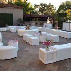 a bunch of white couches sitting on top of a stone floor covered in flowers