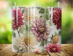 three floral tumblers sitting on top of a wooden table