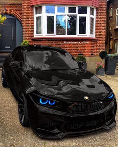 a black car with blue eyes parked in front of a brick building