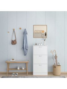 a white cabinet sitting next to a wooden bench in a room with blue walls and wood flooring