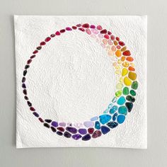 a colorful circle made out of stones on a white wall