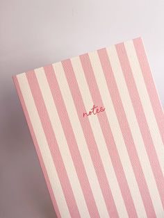 a pink and white striped notebook with the word notes written on it's cover