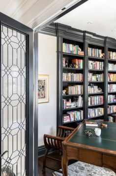 a room with many bookshelves and desks in front of glass doors that lead to another room