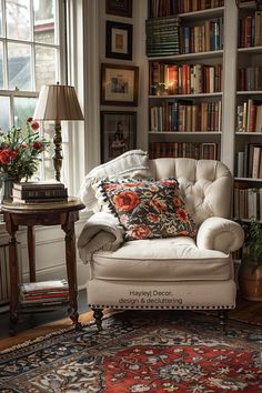 a white chair sitting in front of a window next to a book shelf filled with books