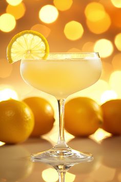 a glass filled with a drink next to some lemons and lights in the background