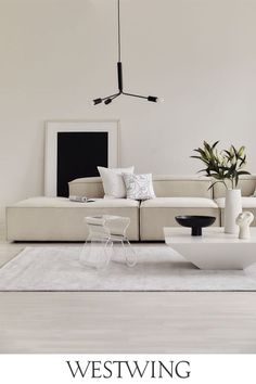 a modern living room with white furniture and plants in vases on the coffee table