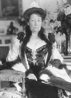 an old black and white photo of a woman sitting in a chair wearing a tiara