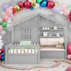 a baby's room with balloons and a bed in the middle, next to a wall that has a house on it