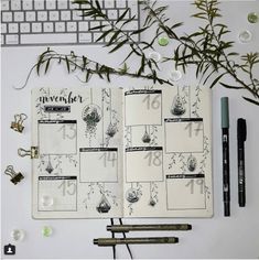 an open planner sitting on top of a white desk next to a keyboard and plant