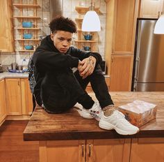 a young man sitting on top of a kitchen counter