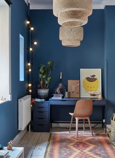 a room with blue walls and a rug on the floor in front of a desk