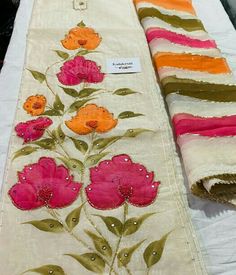 two pieces of cloth with flowers on them sitting on top of a white tablecloth