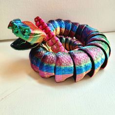 a multicolored snake shaped object sitting on top of a white table next to a wall