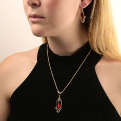 A classic! This alluring gold tone necklace showcases a luscious ruby-red color crystal. Our classic necklace is wonderfully framed with gold tone filigree and hangs perfectly on a 14k gold-dipped adjustable chain. Two smaller crystals punctuate gorgeous gold tone filigree creating a perfect magical medley. It makes an affordable stately gift for her. Navette Faceted Siam Red Stone With Red Crystal Accents Rope Chain With 3-Inch Extension Measurements: 16"L x 1.96"H x 0.61"W 1928 JEWELRY COLLECT Red Jewelry Aesthetic, Filigree Pendant Necklace, Chic Fashionista, 1928 Jewelry, Filigree Pendant, Classic Necklace, Red Jewelry, Gold Dipped, Gold Tone Necklace